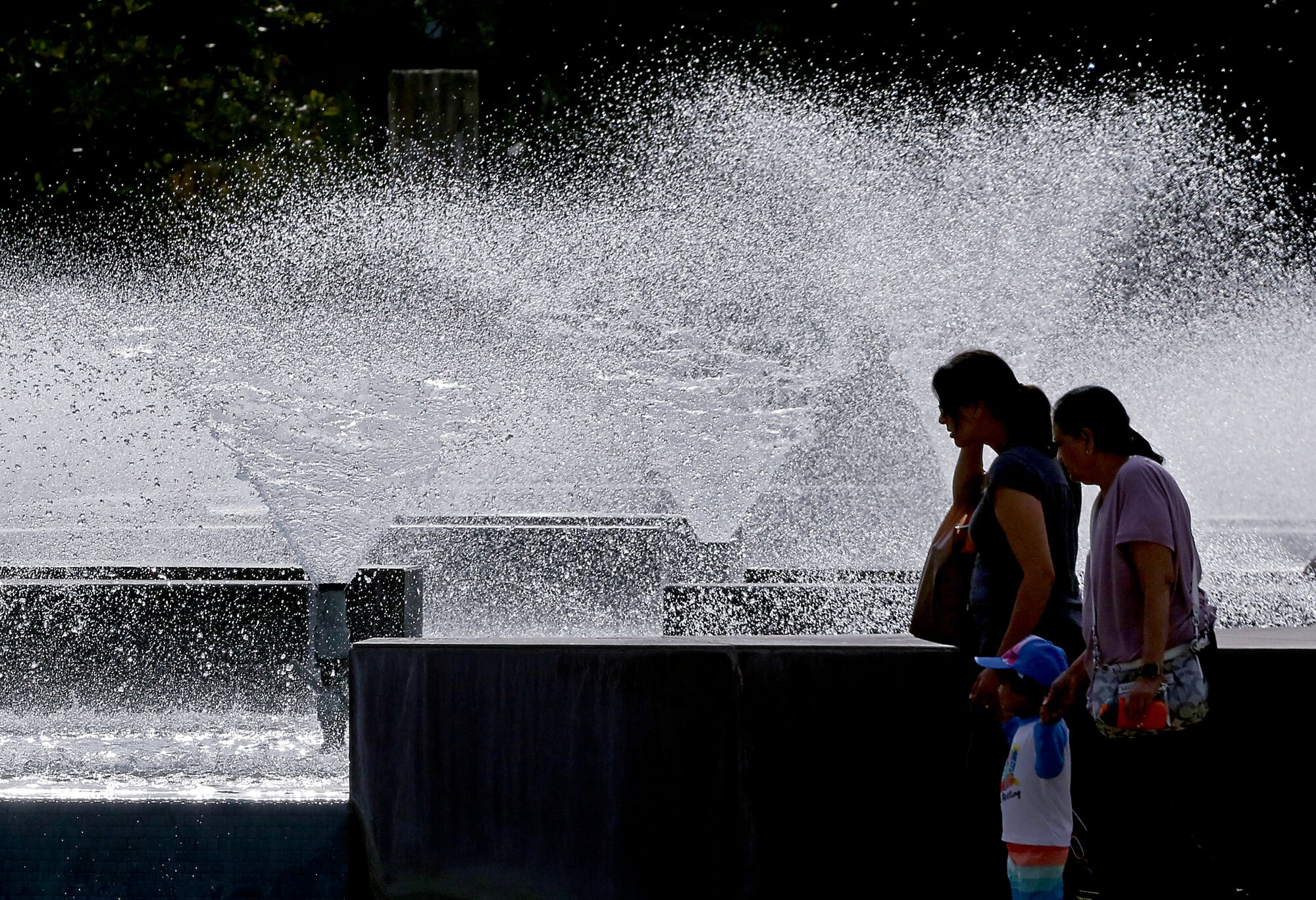 Passersby get some cool mist from a fountain at the Cerritos Civic Center