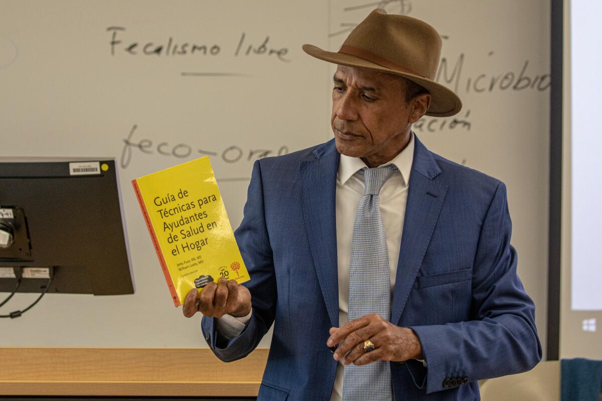 A professor holds up a Spanish-language textbook in class.