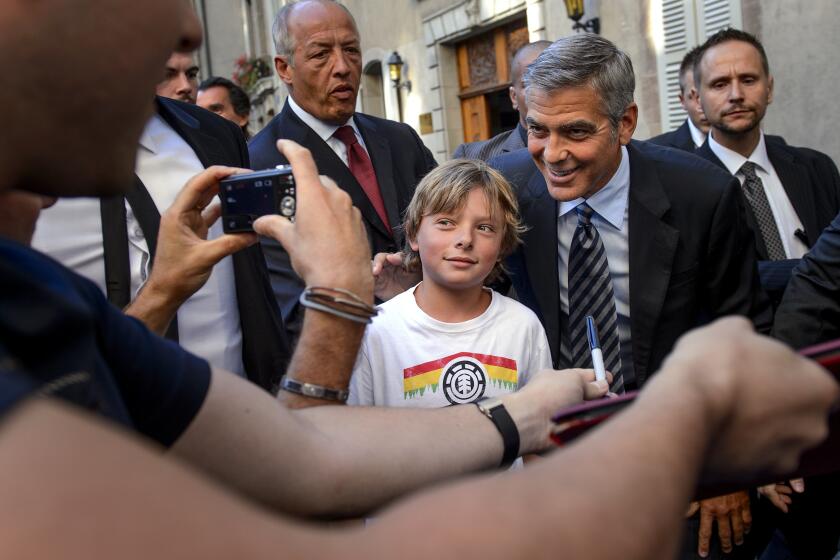 US film star George Clooney (R) poses with a young fan at his arrival on August 27, 2012 in Geneva. Clooney is in Geneva at a fundraiser for US President Barack Obama's re-election campaign. Swiss media said the evening event was limited to US citizens and would begin with a champagne reception for 150 people donating $1,000 (800 euros) each, followed by a dinner for 50 costing $20,000 a head or $30,000 per couple. AFP PHOTO/ FABRICE COFFRINI (Photo credit should read FABRICE COFFRINI/AFP/GettyImages)