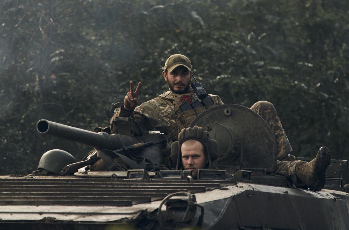 A Ukrainian soldier shows a V-sign atop a vehicle in Izium, Kharkiv region, Ukraine, Tuesday, Sept. 13, 2022. Ukrainian troops piled pressure on retreating Russian forces Tuesday, pressing deeper into occupied territory and sending more Kremlin troops fleeing ahead of the counteroffensive that has inflicted a stunning blow on Moscow's military prestige. (AP Photo/Kostiantyn Liberov)