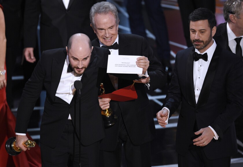 Jordan Horowitz, left, producer of "La La Land," shows the card revealing "Moonlight" as the winner of the best picture Oscar at Sunday's Academy Awards while presenter Warren Beatty, center, and host Jimmy Kimmel look on.