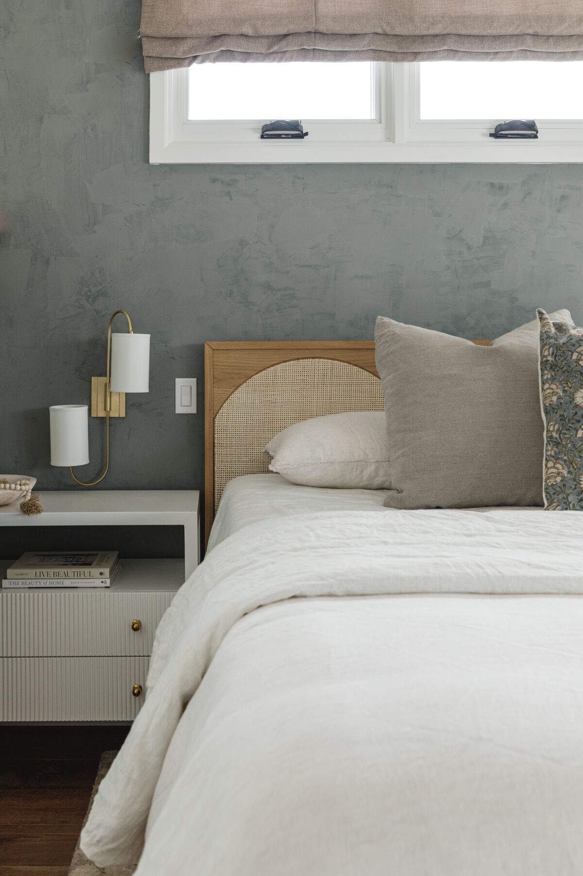 Calming colors and textures are used in bedding and on the walls of a bedroom. 