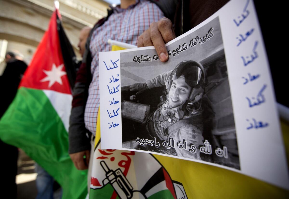 A Palestinian holds a poster with a picture of slain Jordanian pilot, Lt. Moaz Kasasbeh, during a protest in front of the Jordanian Embassy in the West Bank City of Ramallah.