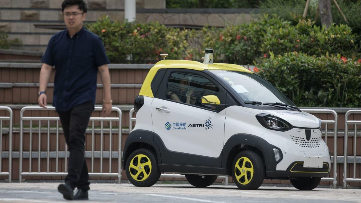 A person walks past a China Mobile Hong Kong and Hong Kong Applied Science and Technology Research Institute (ASTRI) autonomous vehicle, equipped with 5G technology, at the Science Park in Hong Kong on April 17.