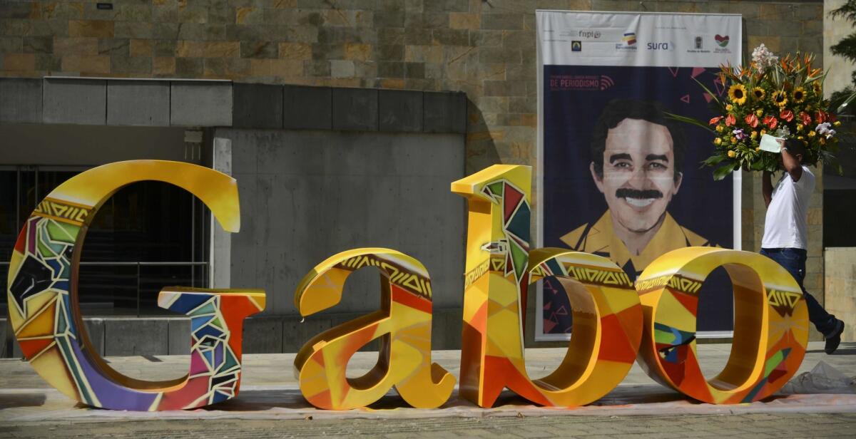A man carries a wreath of flowers as he walks behind a word-shape sculpture reading "Gabo" -- in honor of Gabriel Garcia Marquez -- in Medellin, Colombia, on Sept. 29, 2015.