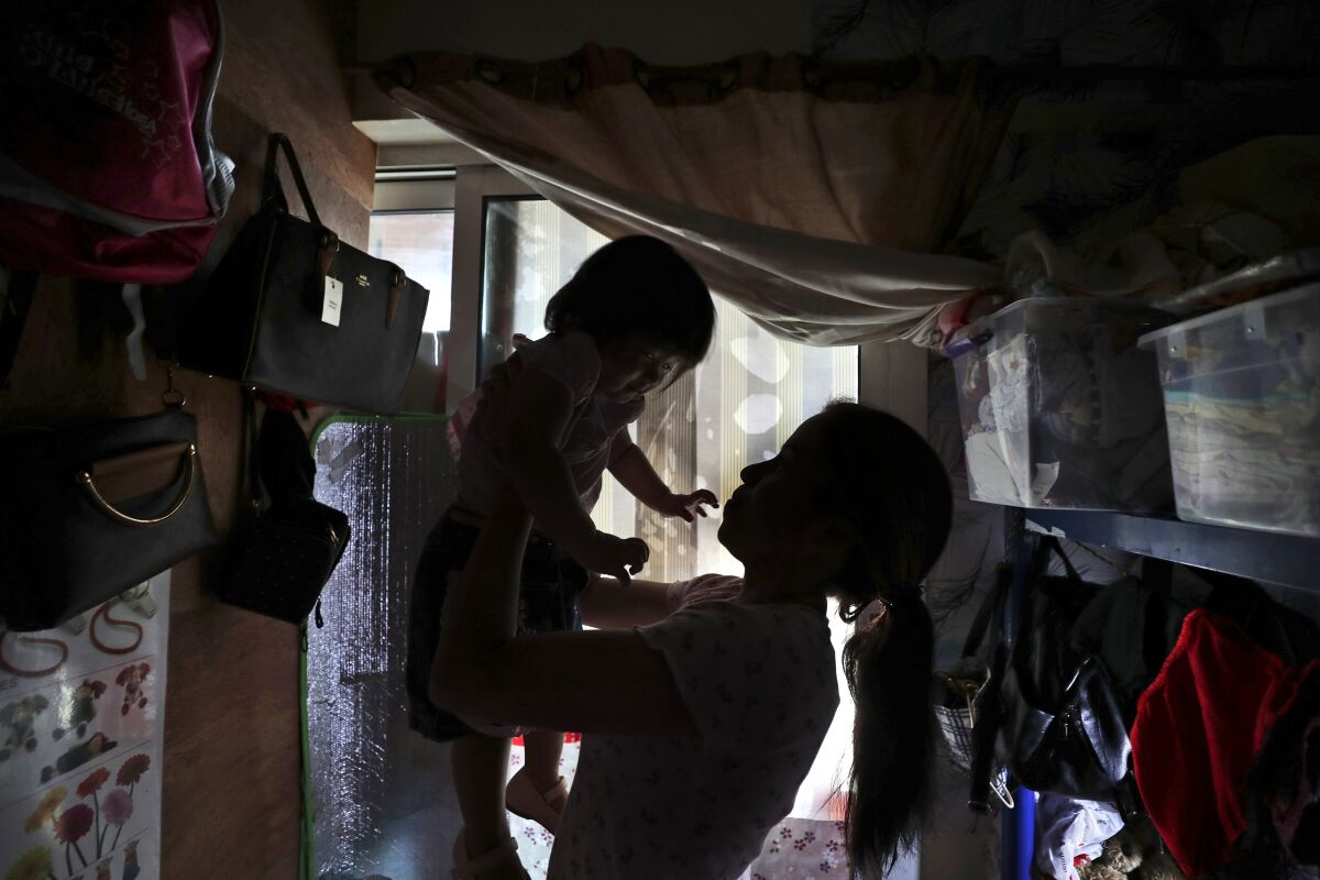 Maya, 36, plays with her one-year-old undocumented daughter in a dank, overstuffed section of an apartment, subdivided by hinged partitions, that she shares with eight other women, in Dubai, United Arab Emirates, Wednesday, Nov. 24, 2021. A year after the United Arab Emirates decriminalized premarital sex in a bold expansion of personal freedoms, the law has struggled to fulfill its promise. Unwed mothers may no longer land in jail, but they're caught in bureaucratic limbo, fighting to obtain birth certificates for their babies born in the shadows. (AP Photo/Kamran Jebreili)