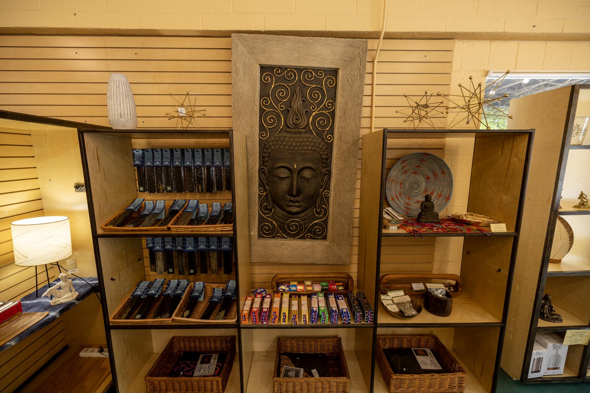 A stone wall hanging depicting Buddha hangs askew.