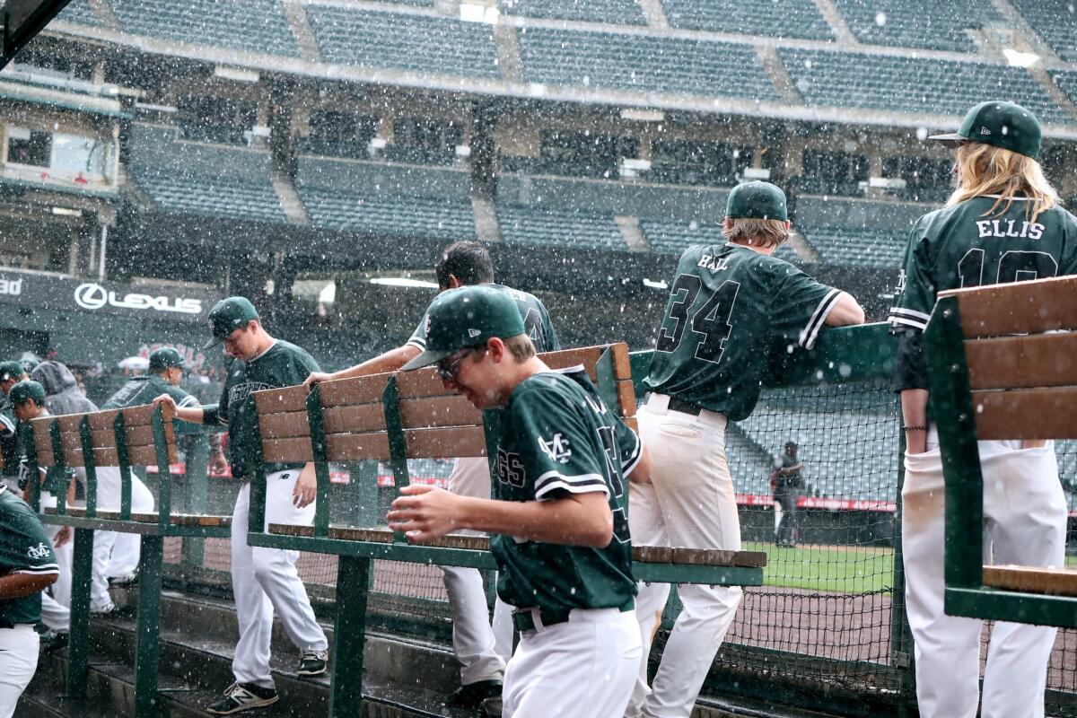 Costa Mesa High players head for cover as it rains and hails in the Halo Classic against Estancia at Angel Stadium on Wednesday.
