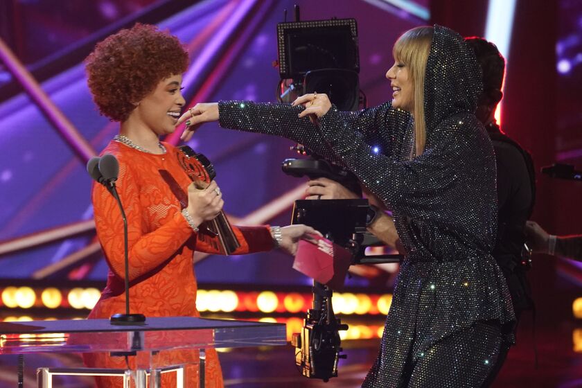 Ice Spice, left, presents an award to Taylor Swift