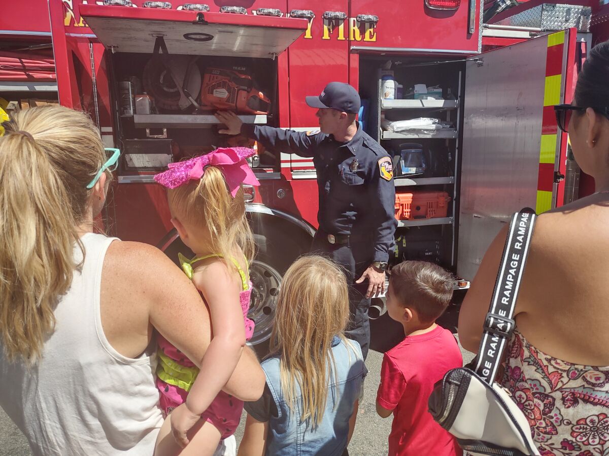Cal Fire Engineer Paramedic Elliott Jenner shows fire truck equipment to kids after the “My Daddy Slays Dragons” reading.