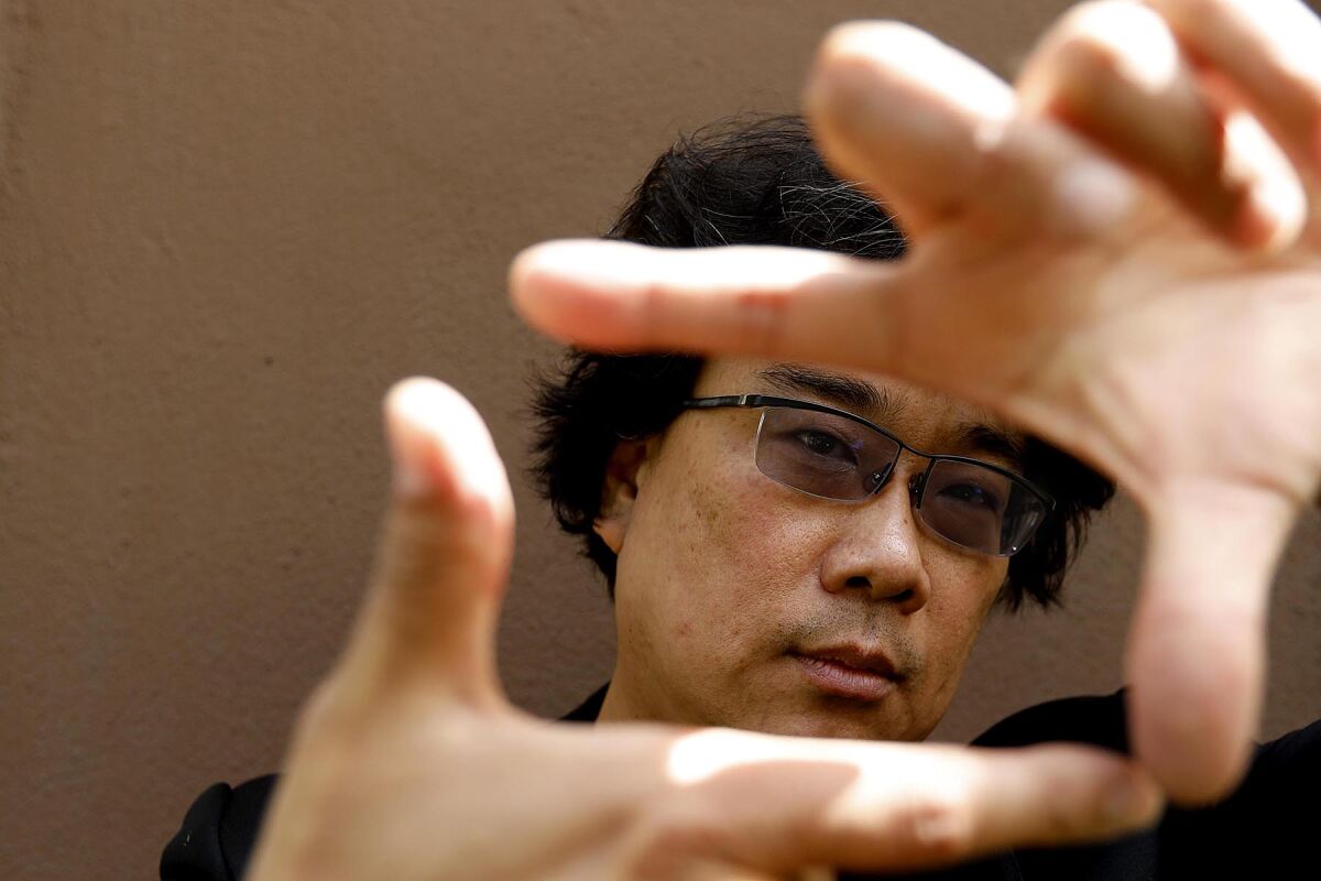 Bong Joon Ho holding his thumbs and forefingers in front of his face in the shape of a frame.