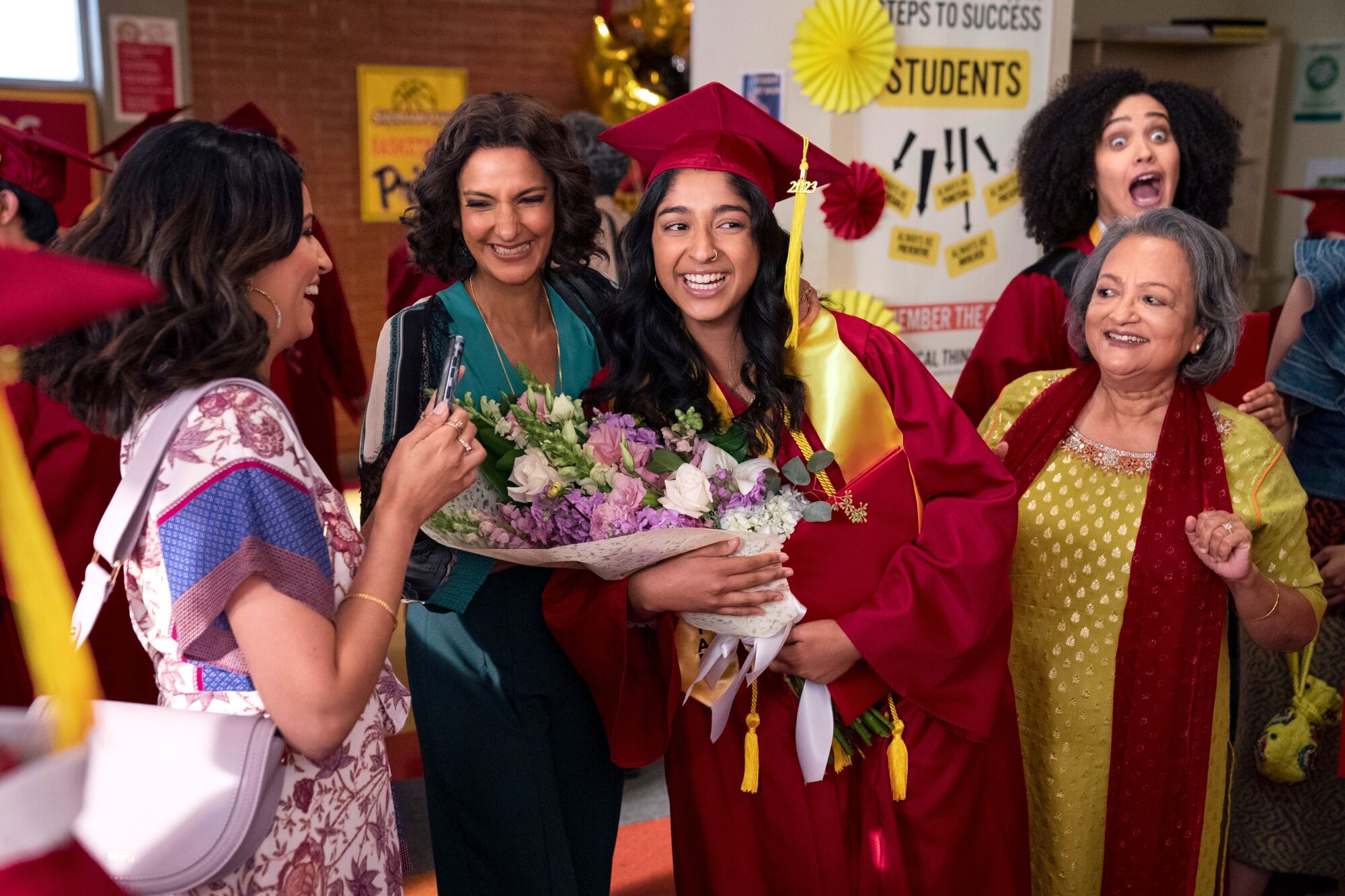 girl in graduation garb holds flowers while her family surrounds her