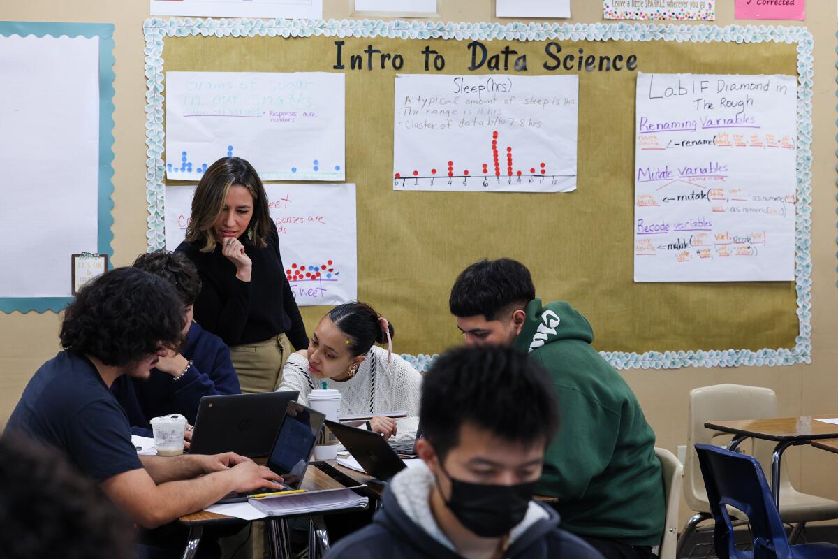 Students work near a bulletin board reading "Intro to Data Science."