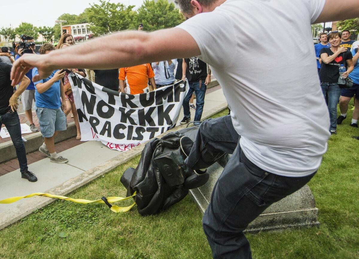 A protester kicks the toppled statue of a Confederate soldier after it was pulled down in Durham, N.C., on Monday.