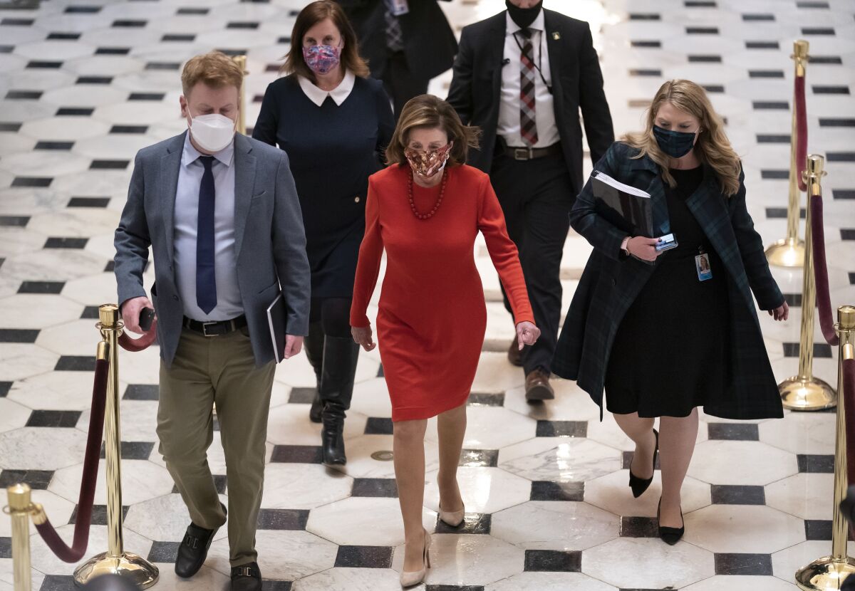Nancy Pelosi walks in the Capitol with a group of aides around her