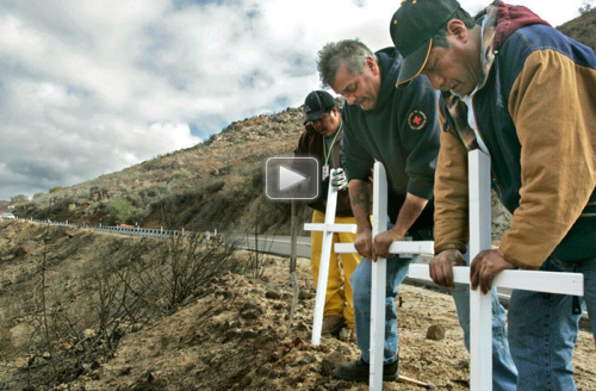 Concepcion Peralta, far right, gets help from the Angeles del Desierto search and rescue group in planting three crosses near the site where his daughter, her husband and a friend died in last October's Harris fire. Watch video >>>