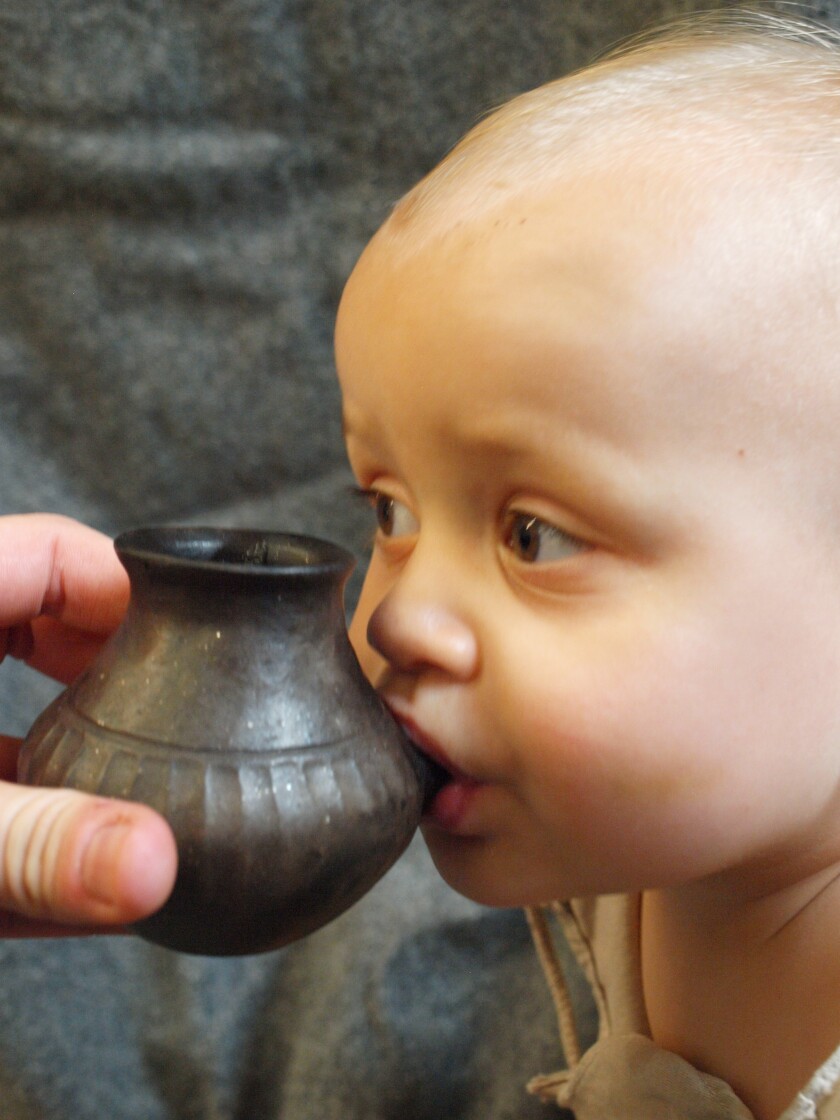 Baby using an infant feeding vessel