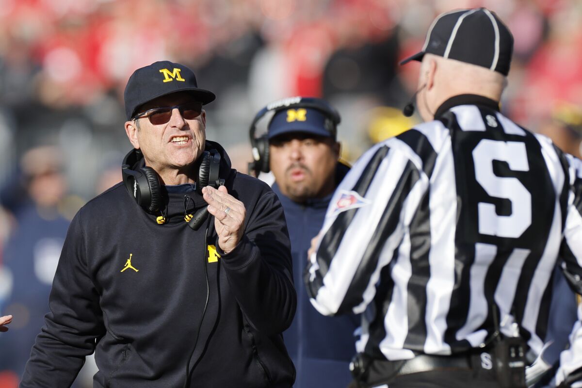 Michigan coach Jim Harbaugh gestures with his hand and argues with a game official during a game.