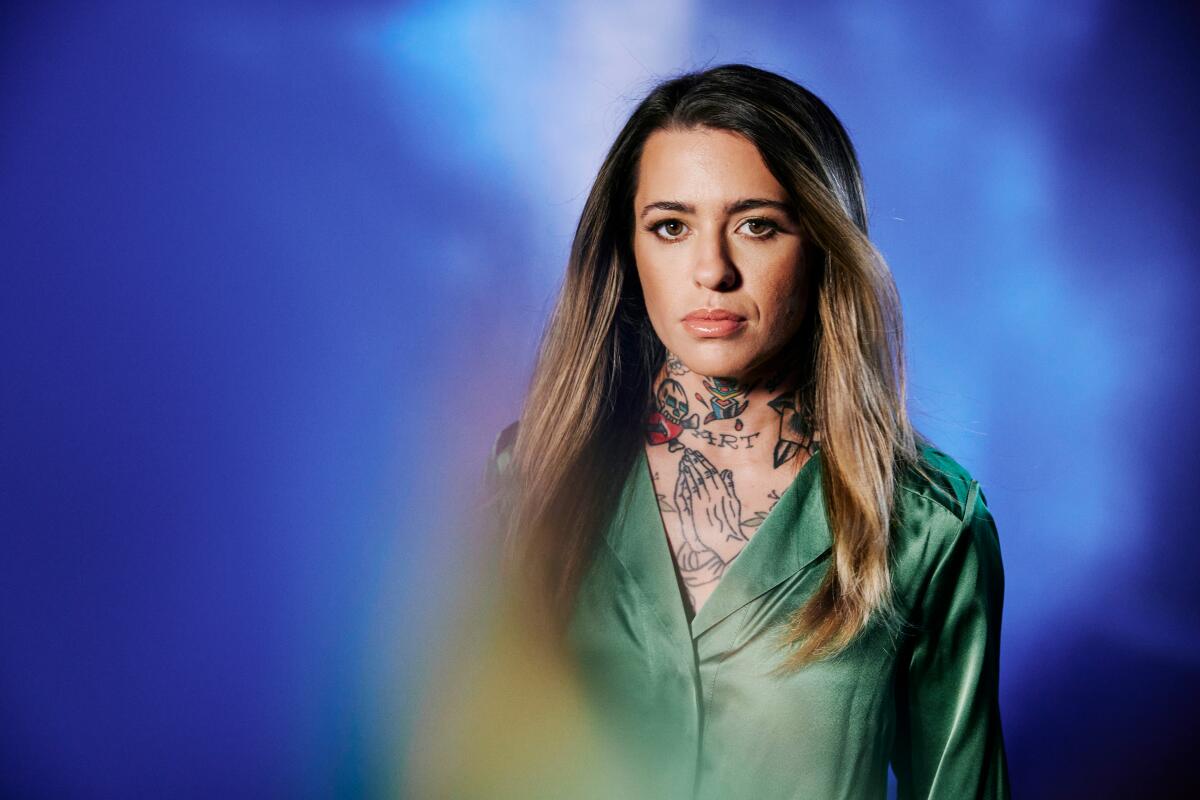 A tattooed female country singer in a green blouse