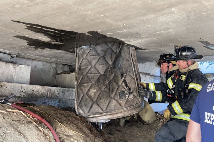 Sacramento firefighters remove a mattress from underneath an overpass on Highway 160.