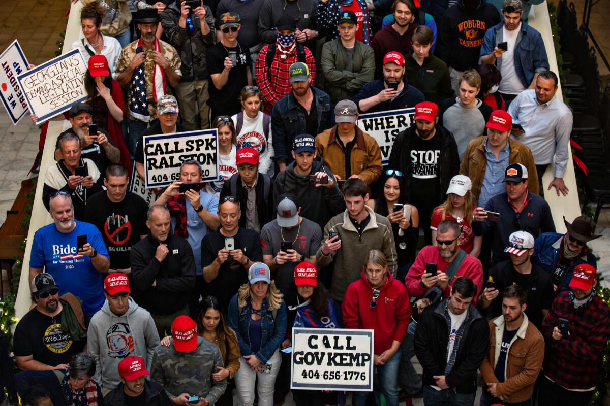 A group of people, many wearing red MAGA caps, at a demonstration