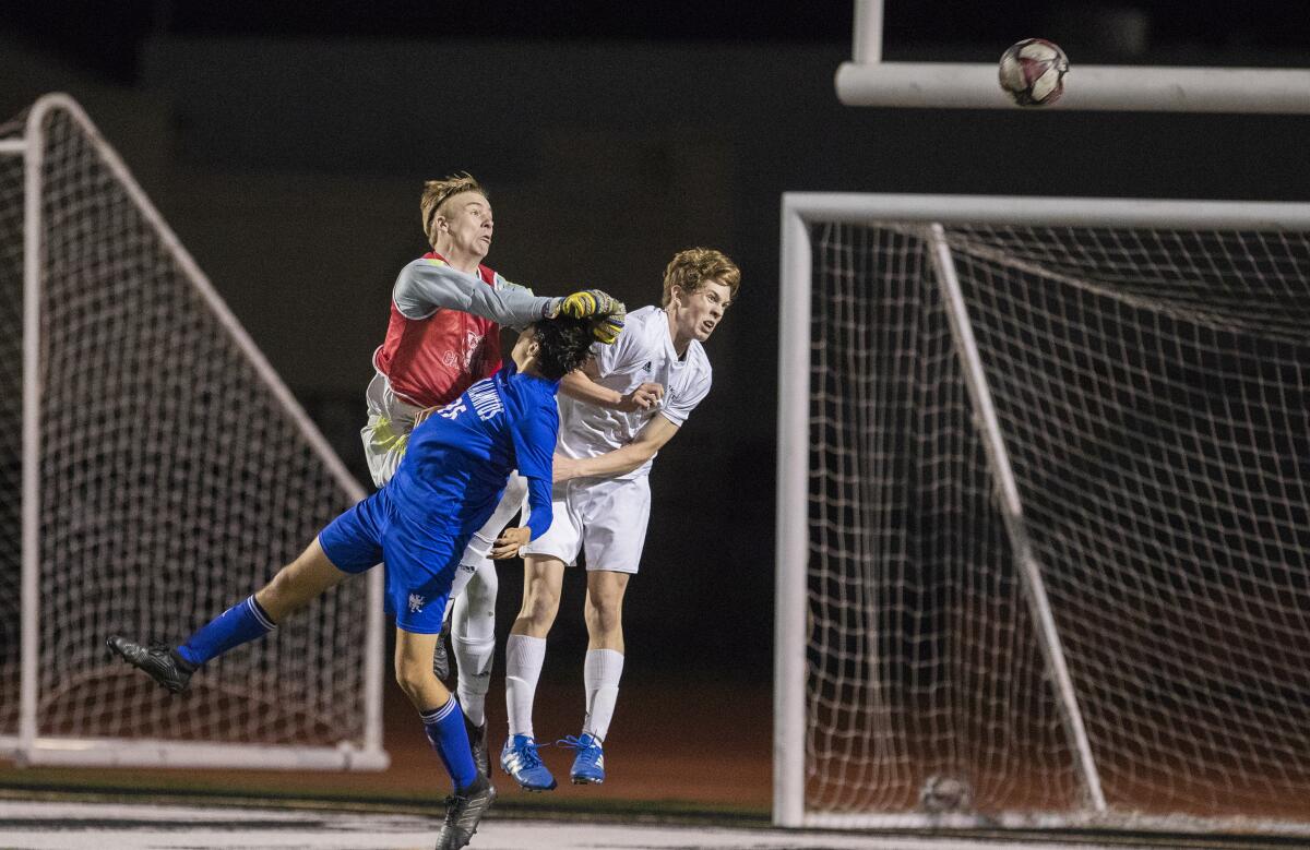 Corona del Mar's goalie Nik Darrough and Thomas Glessing go up for a ball against Los Alamitos' Logan Manfro during a Surf League second-place tiebreaking match on Thursday, Feb. 6.