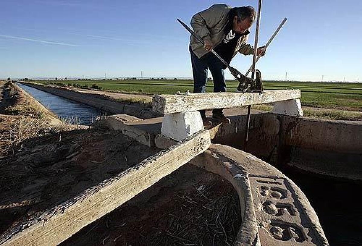 Jose Romo, a zanjero with the Imperial Irrigation District, uses a metal jack to open a gate that controls the release of water into ditches for crops in the Imperial Valley.