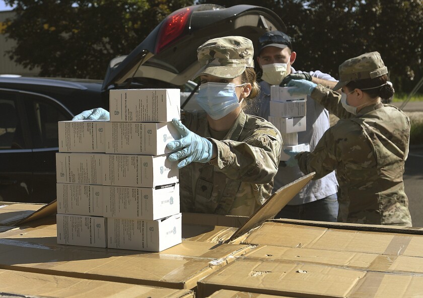 FILE - In this Wednesday, May 27, 2020, file photo, Oregon National Guard's Ashley Smallwood, of Springfield, Ore., counts out boxes of face masks to be given to Willamette Valley farmers while participating in a distribution event at the Oregon State University Extension Service-Linn County office in Tangent, Ore. Oregon adopted a controversial rule on Tuesday, May 4, 2021 that indefinitely extends coronavirus mask and social distancing requirements in all businesses in the state. State officials say the rule, which garnered thousands of public comments, will be in place until it is “no longer necessary to address the effects of the pandemic in the workplace.” (Mark Ylen/Albany Democrat-Herald via AP, file)