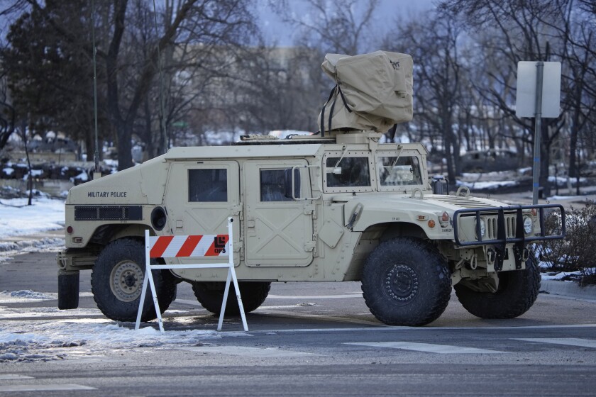 A Colorado National Guard vehicle blocks an entrance to a neighborhood left in rubble by wildfires, Tuesday, Jan. 4, 2022, in Louisville, Colo. (AP Photo/David Zalubowski)