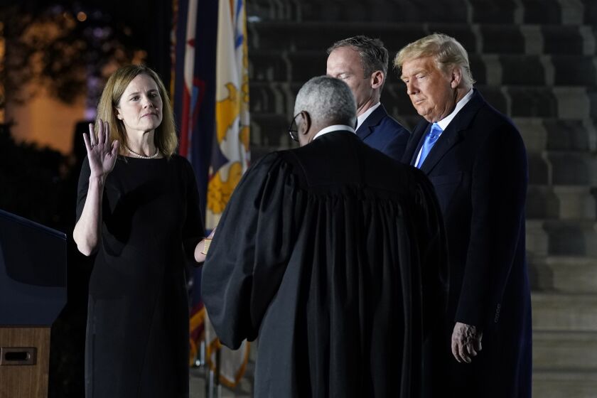 President Donald Trump watches as Supreme Court Justice Clarence Thomas administers the Constitutional Oath to Amy Coney Barrett on the South Lawn of the White House in Washington, Monday, Oct. 26, 2020, after Barrett was confirmed by the Senate earlier in the evening. Jesse Barrett holds the Bible. (AP Photo/Patrick Semansky)