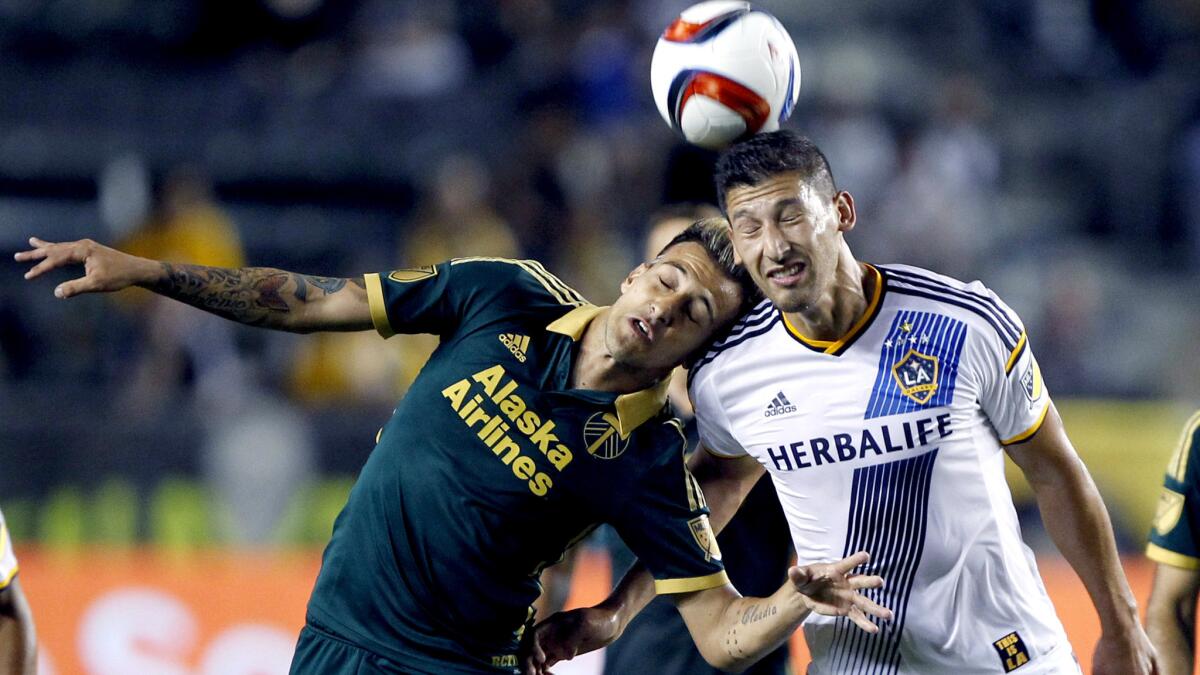 Galaxy defender Omar Gonzalez, right, heads the ball away from Timbers midfielder Maximiliano Urruti during the first half of their game on June 24.