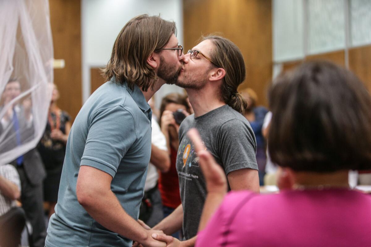 Craig Bowen, left, and Jake Miller kiss Wednesday after being married by Marion County Clerk Beth White, right, in Indianapolis.