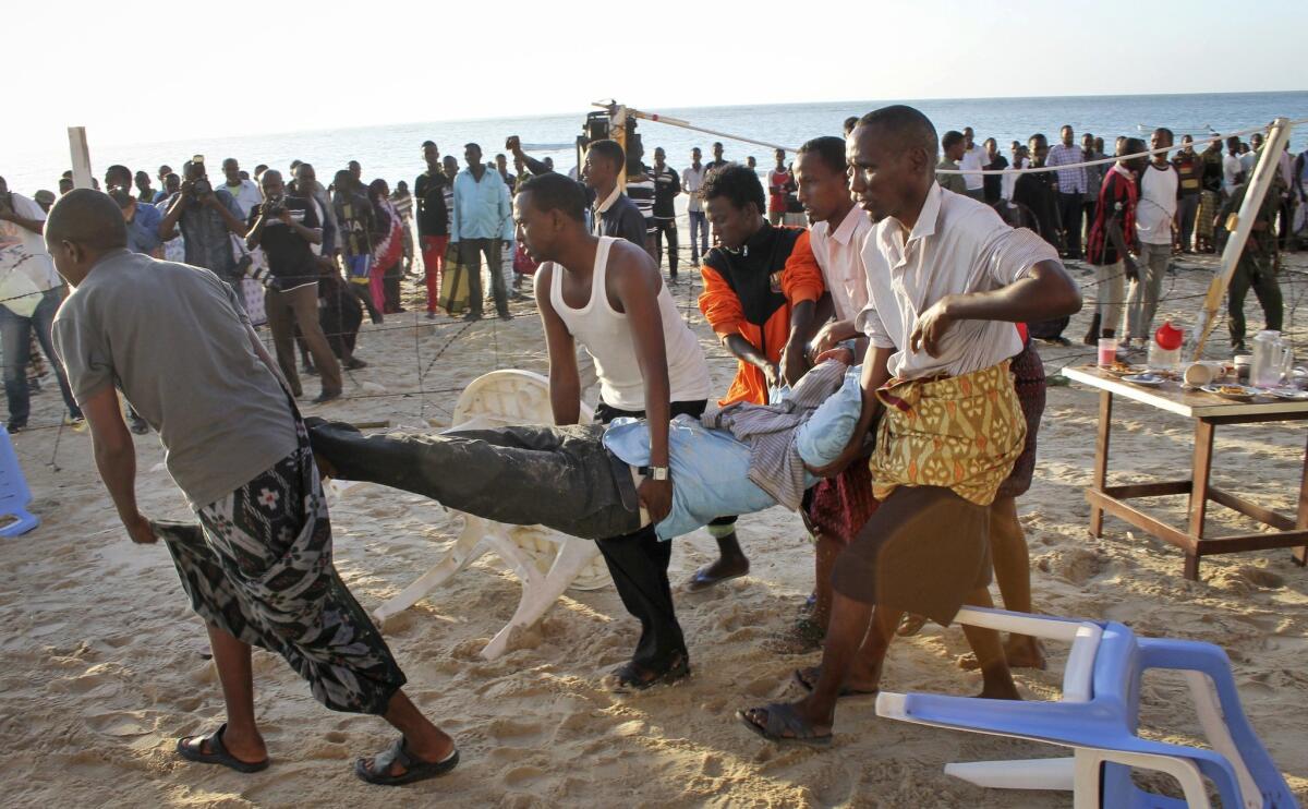 Relatives carry away a dead body from the beach following Jan. 21 attack on a beachfront restaurant in Mogadishu, Somalia.