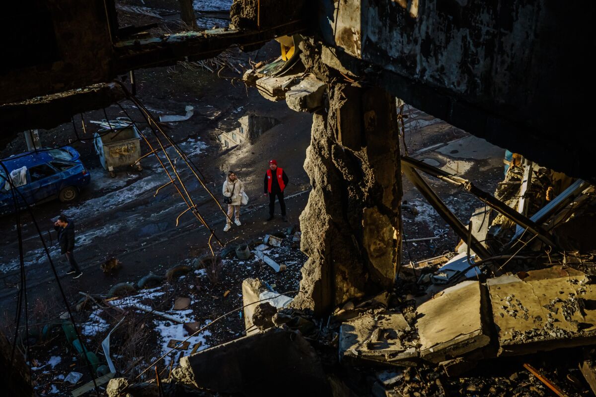 Two people look up at a destroyed apartment building in Kharkiv.