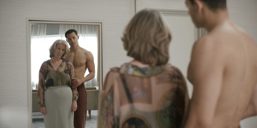 A shirtless man and a woman look in a mirror together.