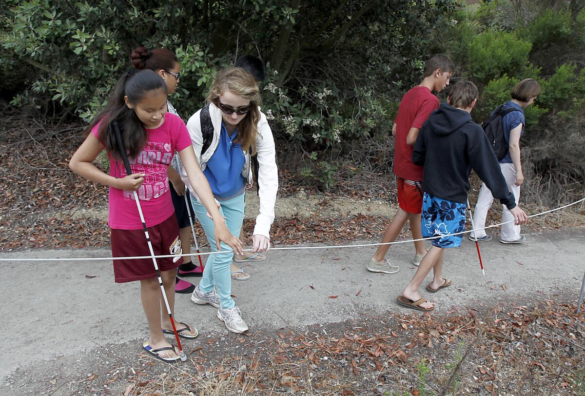Braille Institute teen Veronica Sanchez, left, is led by Youth Assistant Katie Brazer as they begin oa hike of the Study Loop trail at Crystal Cove, Thursday.