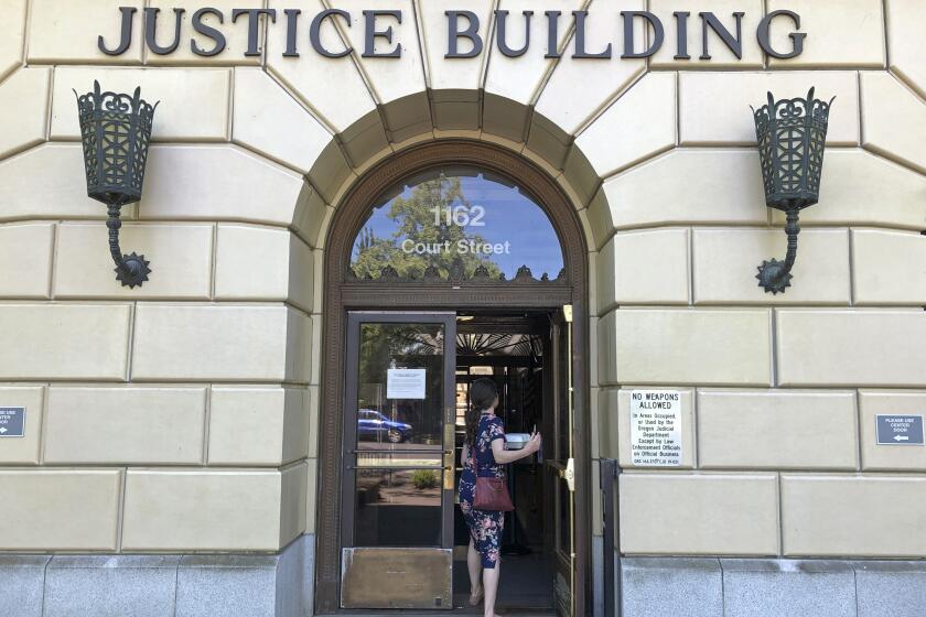 FILE - A woman enters the Oregon Department of Justice building in Salem, Ore., May 28, 2020. According to a ballot measure passed by Oregon voters, state senators who accumulated 10 or more unexcused absences at the Legislature during a record-setting Republican walkout are supposed to be disqualified from running for re-election, but several filed suit in the Oregon Court of Appeals, challenging the measure. On Monday, Sept. 25, 2023, the appeals court formally asked the state Supreme Court to handle the case. (AP Photo/Andrew Selsky, File)