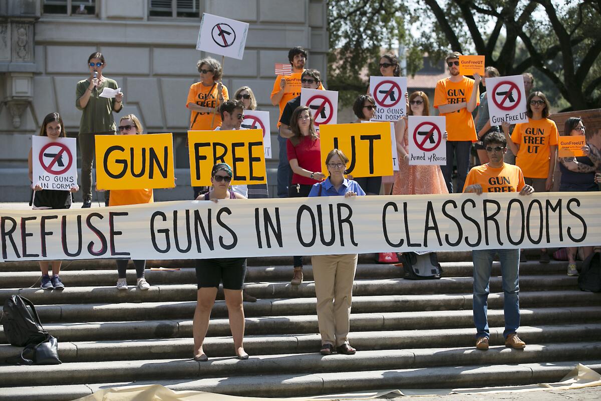 Protesters hold signs at a rally opposing guns on campus at the University of Texas in Austin in October. State law requires public universities in Texas to allow concealed handguns in classrooms and buildings starting Aug. 1.