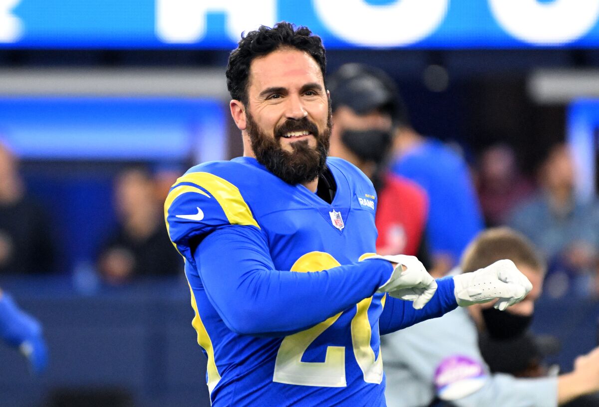 Eric Weddle, with his helmet off before a game, stretches his arms 
