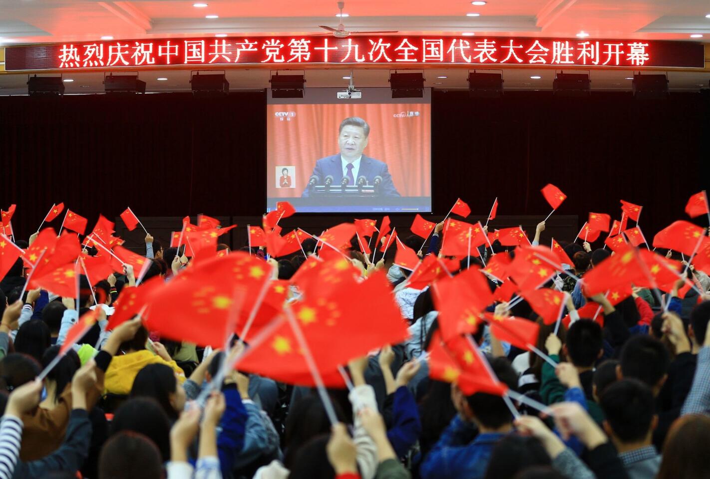 College students wave national flags as they watch the opening of the 19th Communist Party Congress in Huaibei in China's eastern Anhui province.