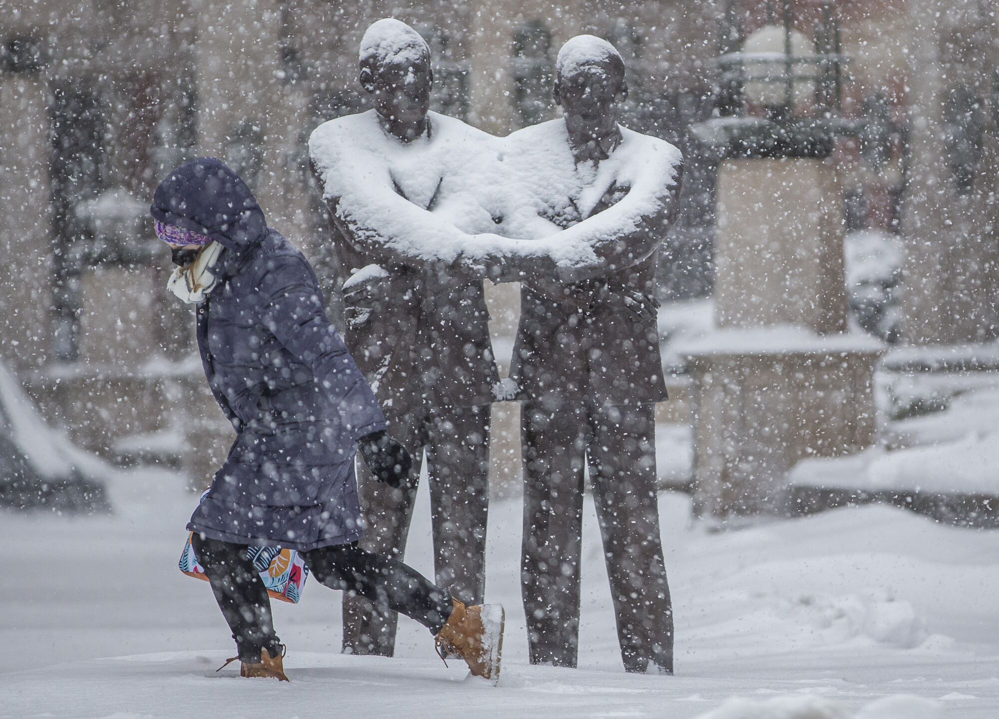 A person walks past a statue amid a snowstorm