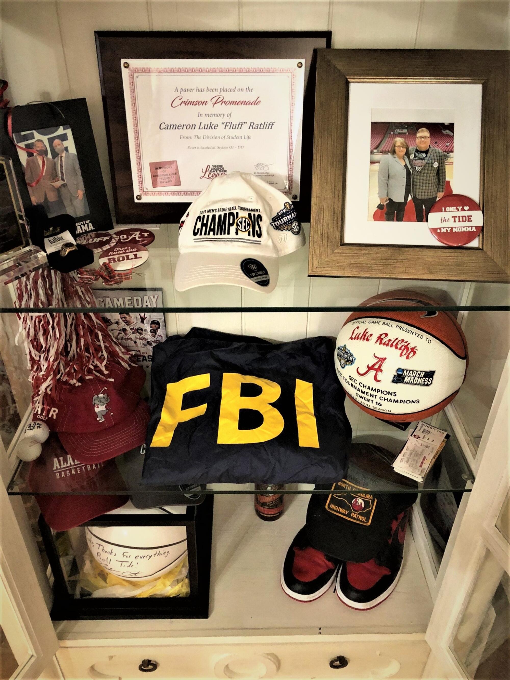 Luke Ratliff's prank FBI jacket, personalized basketballs and other mementos sit in a cabinet.