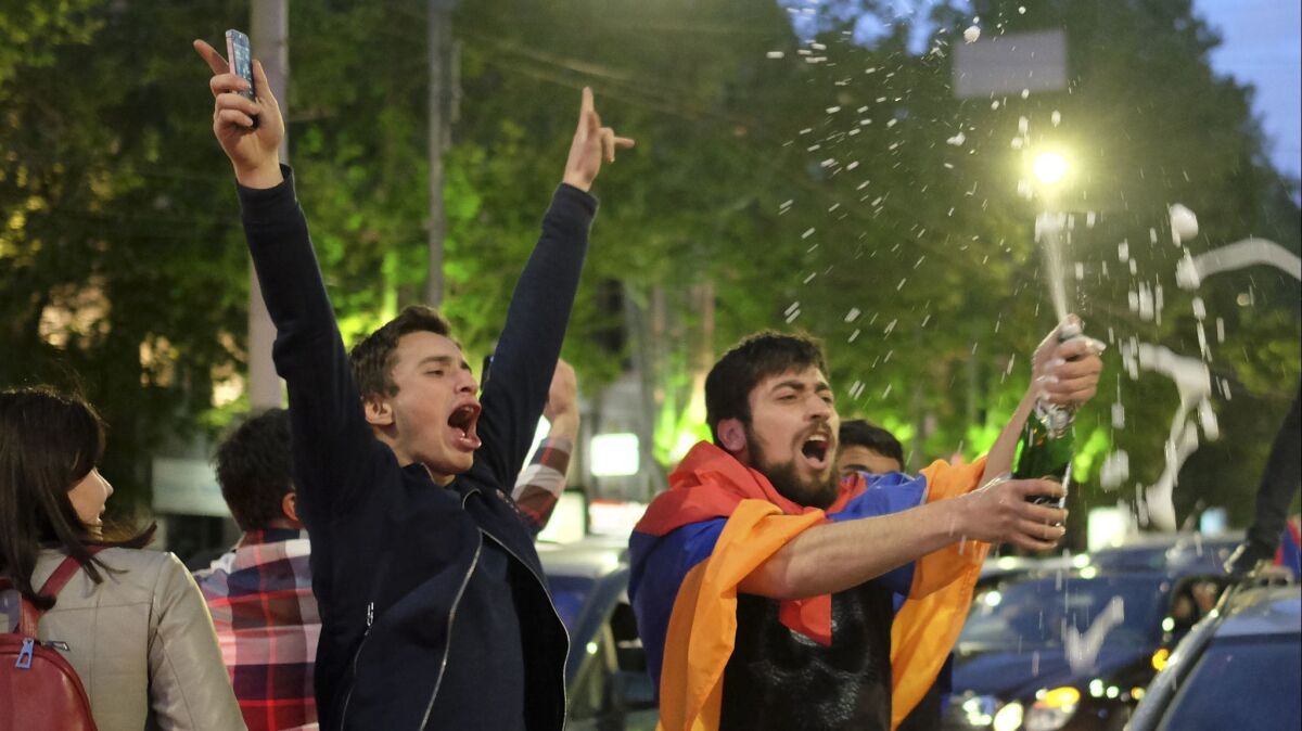 A man with a national flag around his shoulders brandishes a bottle of sparkling wine in Yerevan to celebrate the resignation of Armenian Prime Minister Serzh Sargsyan on April 23, 2018.