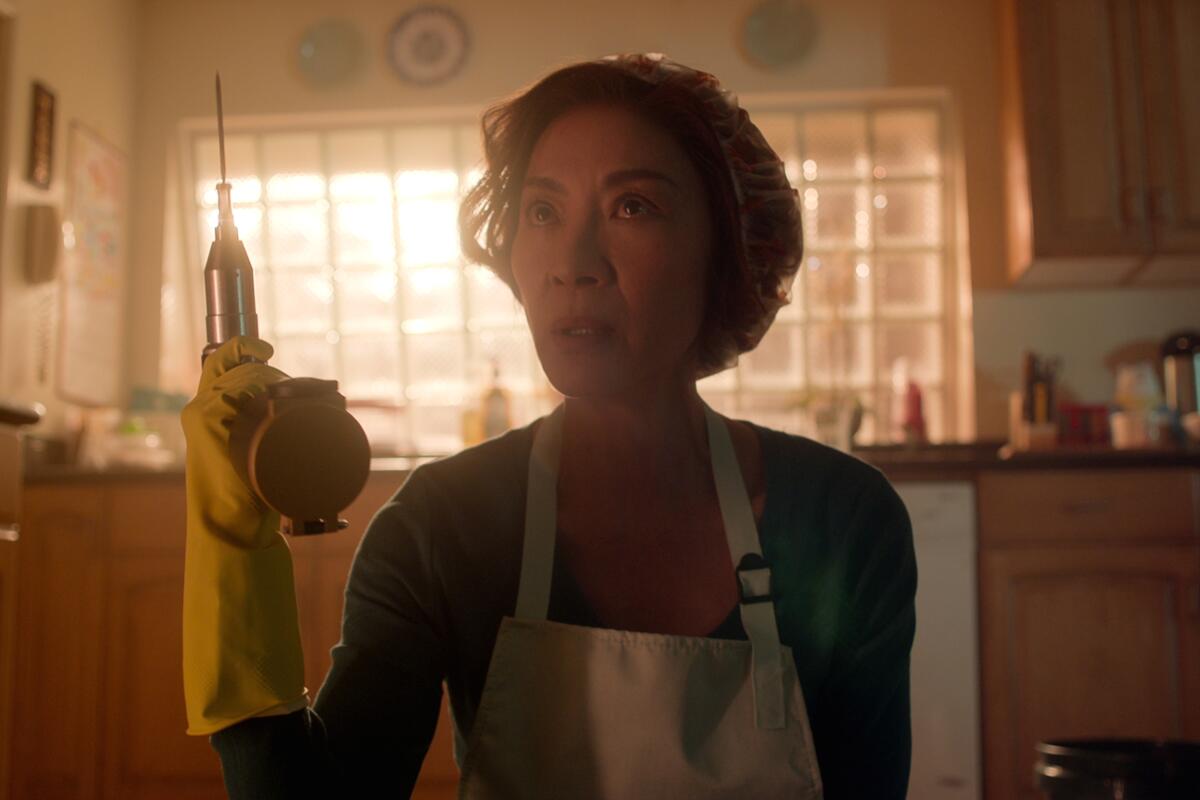 A woman in yellow rubber gloves and an apron holds an electric saw.