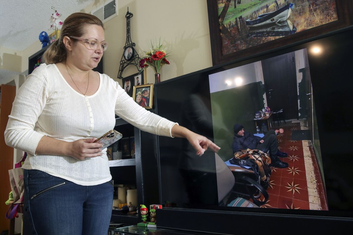 A woman pointing to a photo of her father on a TV screen
