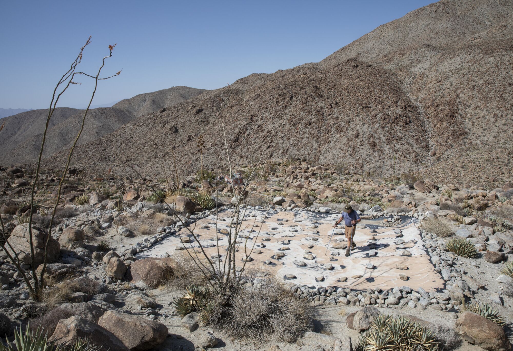 A tarp in the desert is weighted down with rocks.