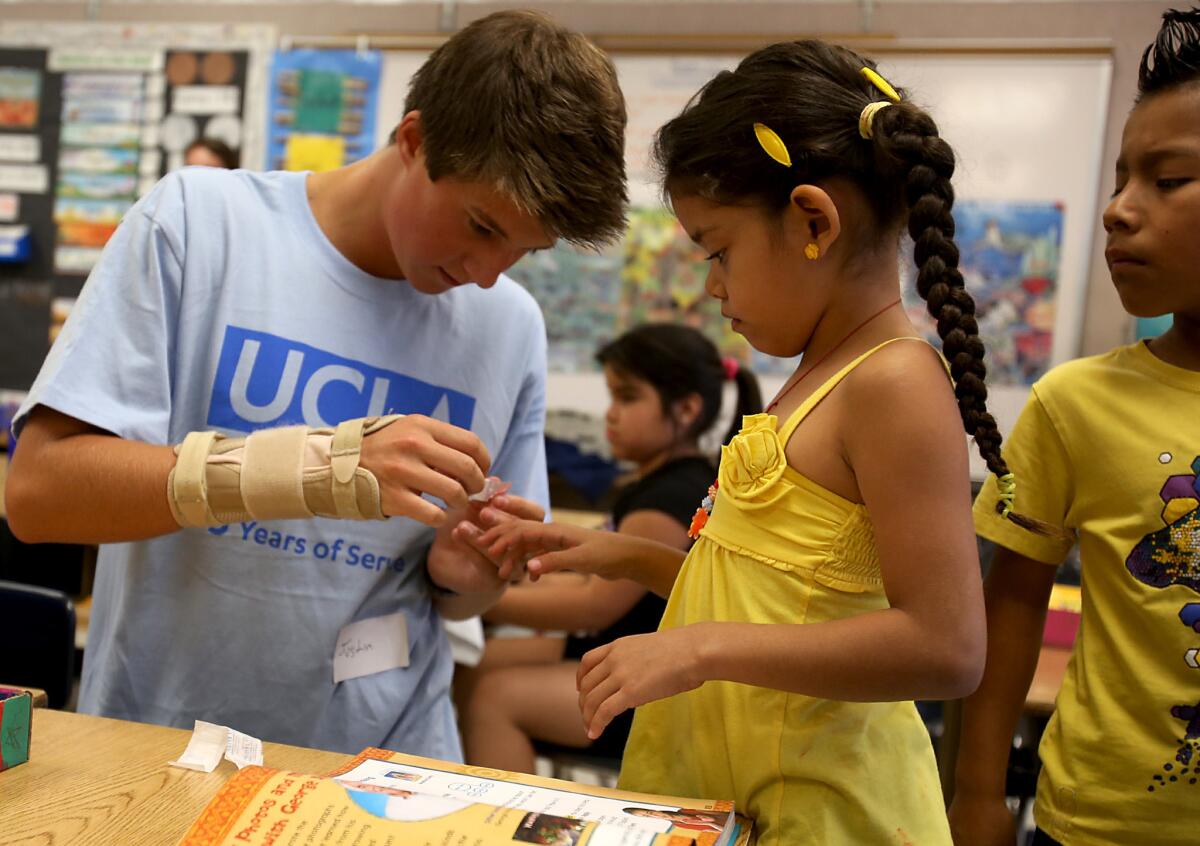 A UCLA student puts a band-aid on a second-grader during UCLA's annual Volunteer Day at Leo Politi Elementary School in the Pico-Union district in 2013.
