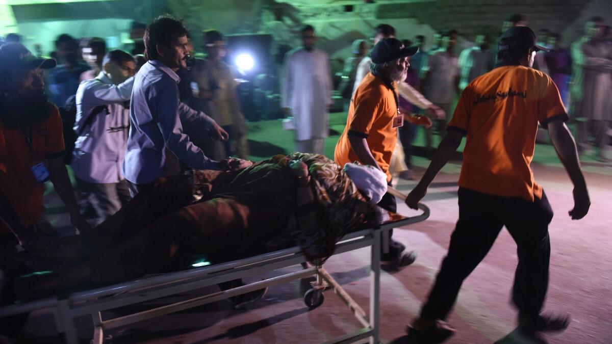 A Pakistani rescuer worker helps the victim of an attack on a Sufi shrine in the city of Karachi on Saturday.