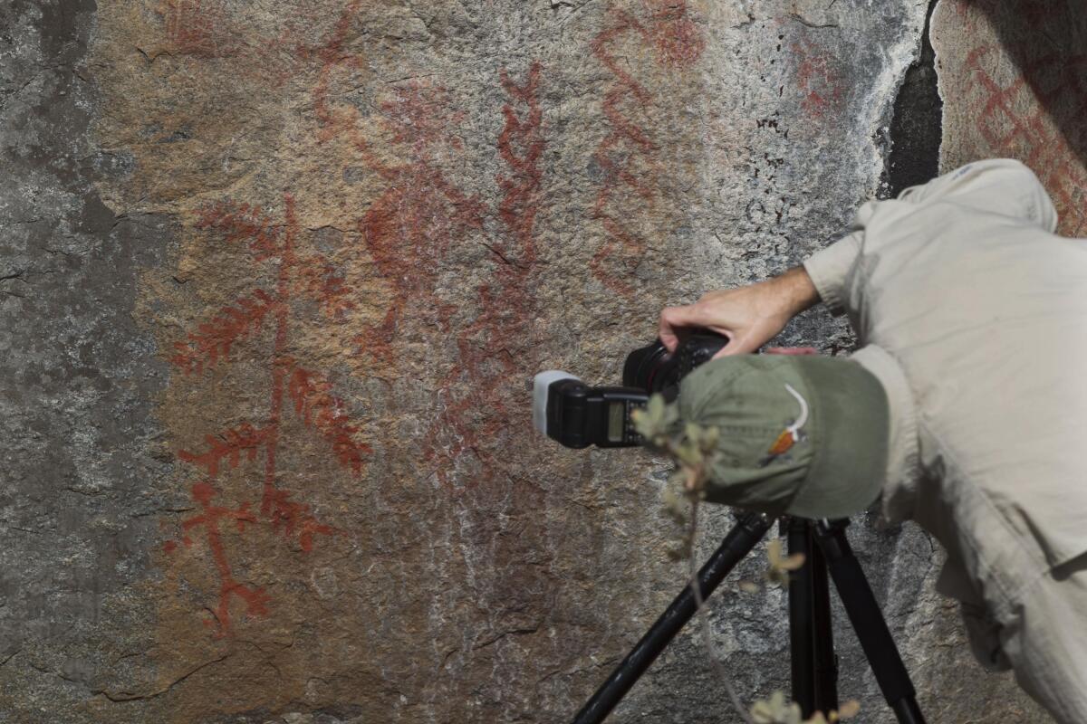 Indigenous rock art expert Steve Freer is shown photographing the main figures of rock art 