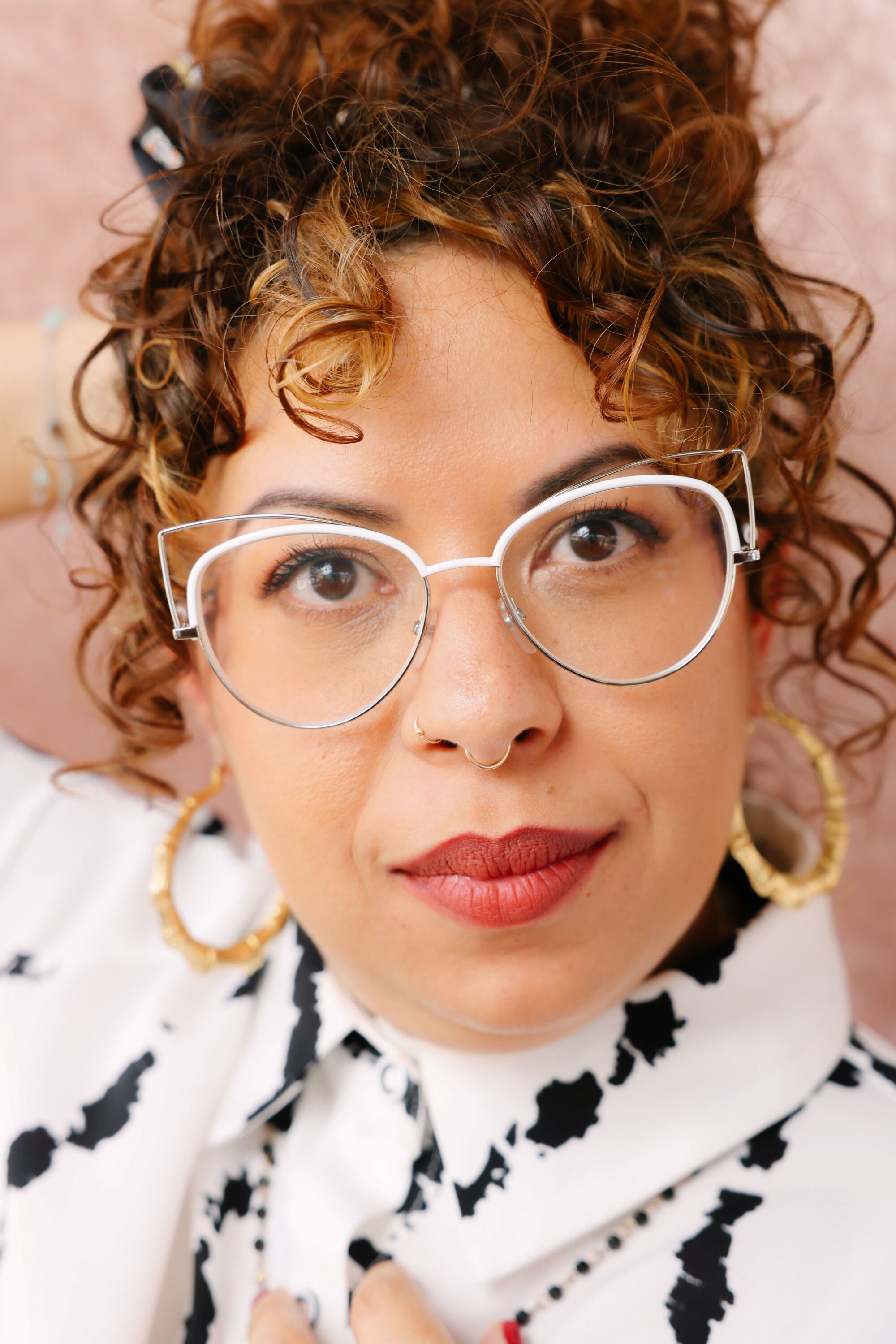 A woman with white framed glasses and red lipstick poses for a portrait